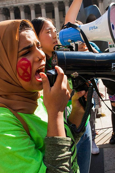 Women speaking into a bullhorns at a rally.