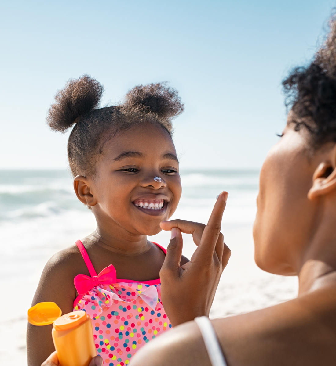 parent applying sunblock to childs face at the beach